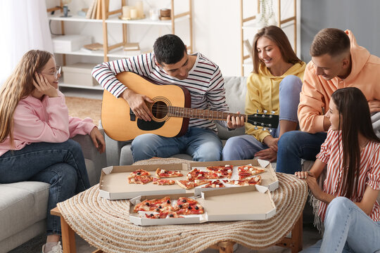 Young man playing guitar for his friends in living room