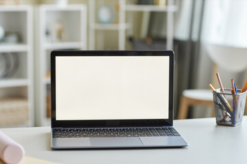 Open laptop with blank white screen mockup on students desk
