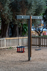 Empty wooden swing in outdoor playground for children in the park, Barcelona, Spain.