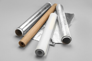 Rolls of aluminium foil and baking paper on grey background