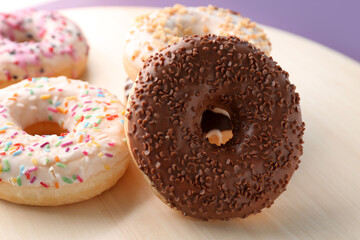 Wooden board with sweet donuts, closeup