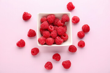 Bowl of fresh ripe raspberry on pink background