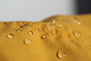 Waterproof fabric with water drops, macro detail of water drops on yellow waterproof jacket...