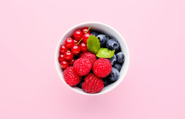 Bowl of fresh ripe berries on pink background