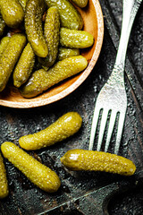 Wooden plate with pickles. On a black background.