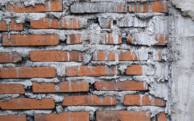 Old distressed red brick wall with gray mortar dripping down on side. Background and wallpaper texture