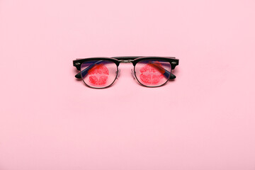 Naklejka premium Eyeglasses with lipstick kiss marks on pink background