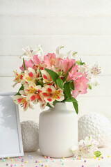 Vase with beautiful alstroemeria flowers and decor on light table. Mother's day celebration