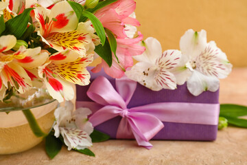 Obraz na płótnie Canvas Vase with beautiful alstroemeria flowers and gift box on color background, closeup. Mother's day celebration