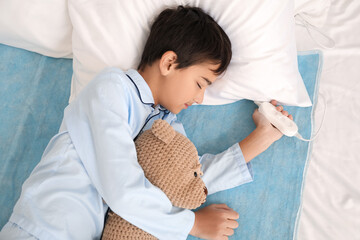 Little boy with toy sleeping on electric heating pad in bedroom © Pixel-Shot
