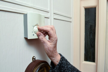 Mature woman turns down the central heating at home to save money