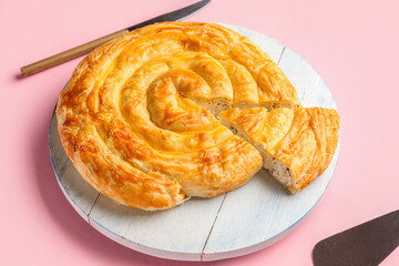 Board with delicious cheese pie on pink background