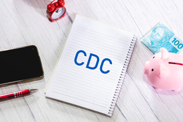 A sigla CDC referente ao Código de Defesa do Consumidor escrita em um caderno que está sobre uma...