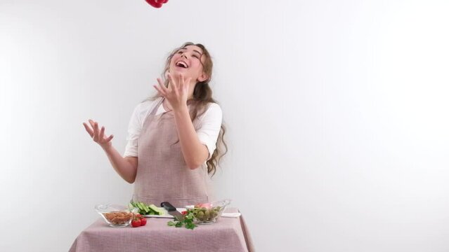 slow motion full HD 240fps young girl woman tossing red bell pepper laughing sincerely on white background space and place for text cooking show cooking appetite delicious vegetable salad vegetarian