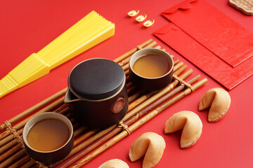 Fototapeta na wymiar Teapot, cups of tea, envelopes and Chinese symbols on red background, closeup