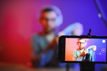 Panoramic view of young adult vlogger creating internet content, holding carton box in hands, unpacking received pack and recording media online video on broadcast equipment