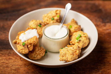 Cauliflower wings food. Pieces of flour-fried cauliflower with vegan sauces on a plate. Wooden background. Vegetarian food.