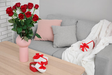 Vase with roses and gifts for Valentine's Day on table in living room