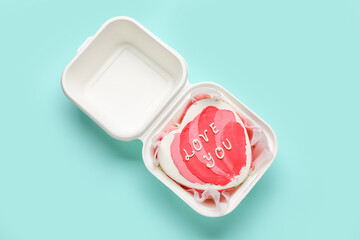 Obraz na płótnie Canvas Plastic lunch box with heart-shaped bento cake on turquoise background. Valentine's Day celebration