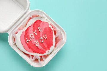Plastic lunch box with heart-shaped bento cake on turquoise background. Valentine's Day celebration