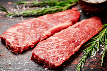 Raw steak with rosemary and spices on the table. 