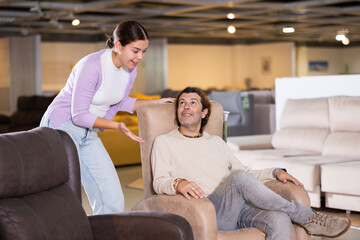 Man and woman sitting around in armchairs in furniture store
