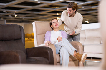 Couple spend their time in the furniture salon looking for a new armchair. High quality photo