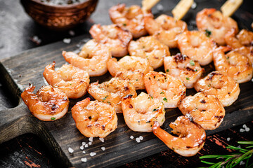 Delicious grilled shrimp on a cutting board with rosemary and spices. 