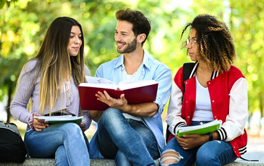 Fototapeta na wymiar Three multiethnic students studying together sitting on a bench outdoor