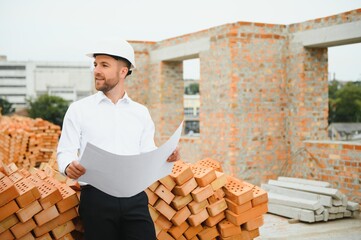 Engineering Consulting People on construction site holding blueprint in his hand. Building inspector. Construction site check drawing and business workflow of new building.