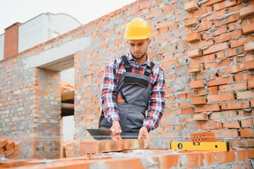 Installing brick wall. Construction worker in uniform and safety equipment have job on building