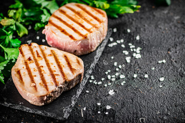 Grilled tuna on a stone board with parsley and salt. 