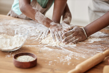 Mother and daughter baking together in kitchen and kneading dough