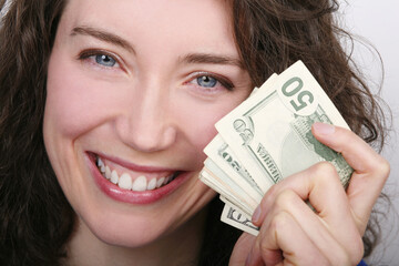 Portrait of attractive happy young woman holding up American paper money against white background.