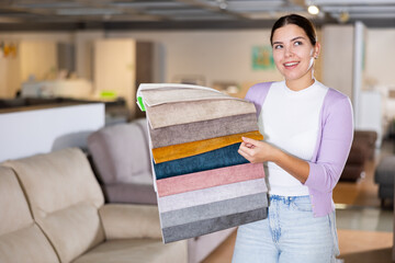 Woman choosing material for sofa in furniture showroom