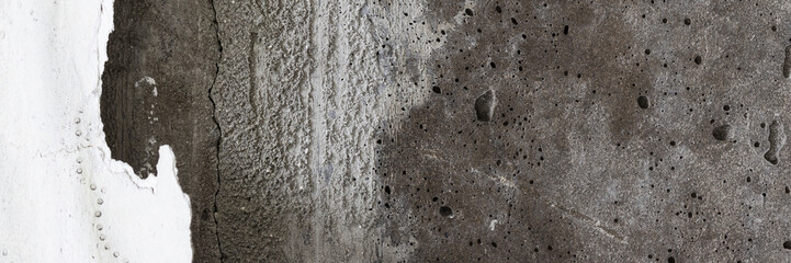 Texture of old cracked concrete wall. Rough gray concrete surface with torn remnants of paper Wallpaper. Wide panoramic background for design.