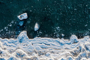 Top view of the freezing sea. Winter aerial photograph of the icy coast and ice floes in sea water....