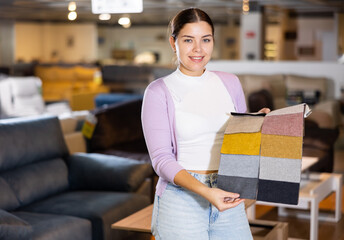 Young woman shows upholstery fabric in the furniture shop