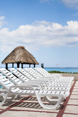 Lounge sunbeds near swimming pool at poolside, outdoor near caribbean sea