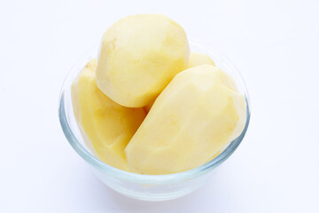 Raw peeled potatoes in glass bowl on white background