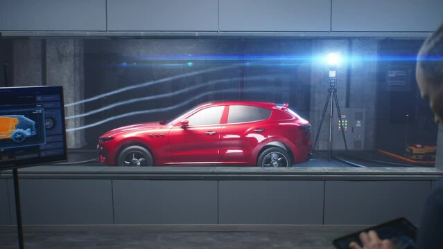 Testing aerodynamics of new generation eco-friendly electric car in lab using wind tunnel with steam. Digital tablet, LED screen with vehicle 3D model. Concept of car testing and modern technologies.