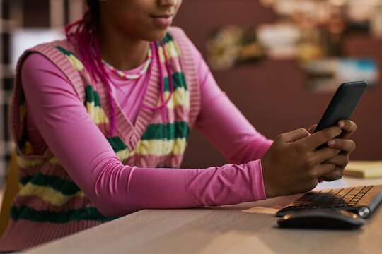 Close up black teenage girl using smartphone at home texting friends