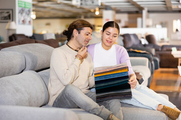 Portrait of couple choosing upholstery fabric in furniture salon shopping room