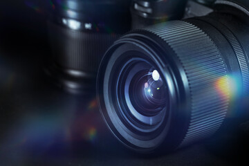 Fototapeta na wymiar Digital photography, lens of a black camera with reflections and flares against a dark background, technical equipment for business and art, copy space, selected focus