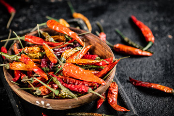 Multicolored pods of dried chili peppers on a cutting board. 