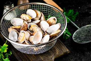 Vongole in a colander on a cutting board with parsley. 
