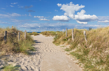 Weg mit Zäunen durch Dünen zum Strand an der Ostsee mit blauem Himmel mit Wolken bei Heiligenhafen, Schleswig-Holstein