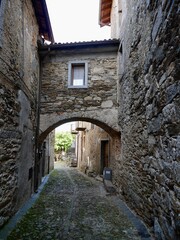 Narrow street with typical stone houses in Cavandone, Piedmont, Italy.