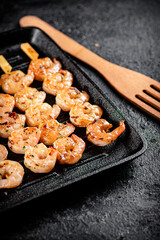 Shrimp on skewers are grilled in a grill pan. 
