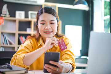 Young woman holding credit card and using laptop computer. Businesswoman working at cafe. Online shopping, e-commerce, internet banking, spending money